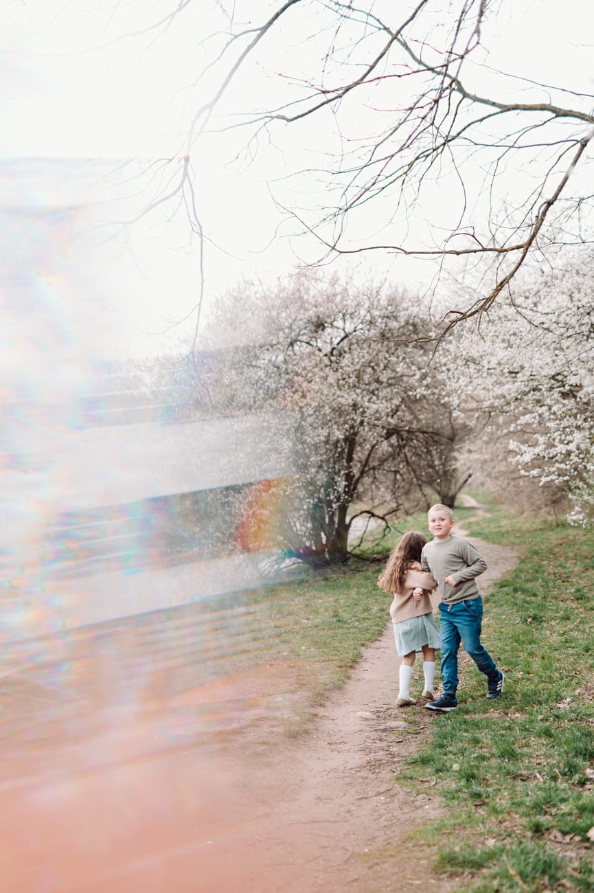 Dzieci tańczą na alejce w kwiatkach sesja wiosenna