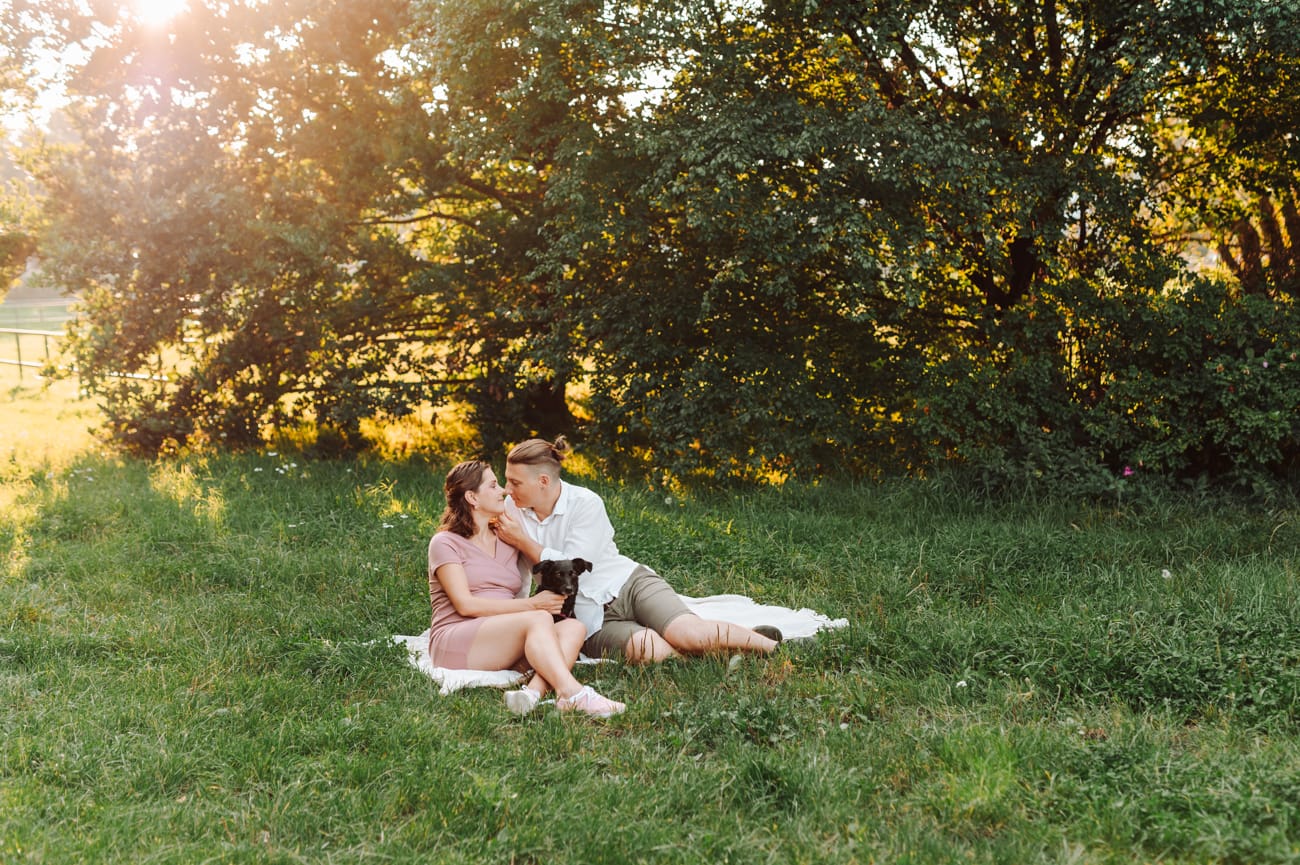 Para z psem na łące zachód słońca sesja ciążowa