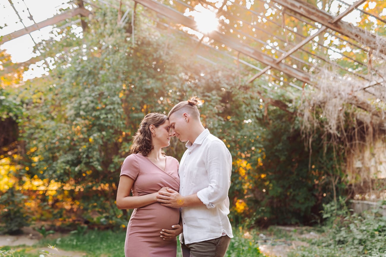 Para przytulona w szklarni sesja ciążowa w plenerze