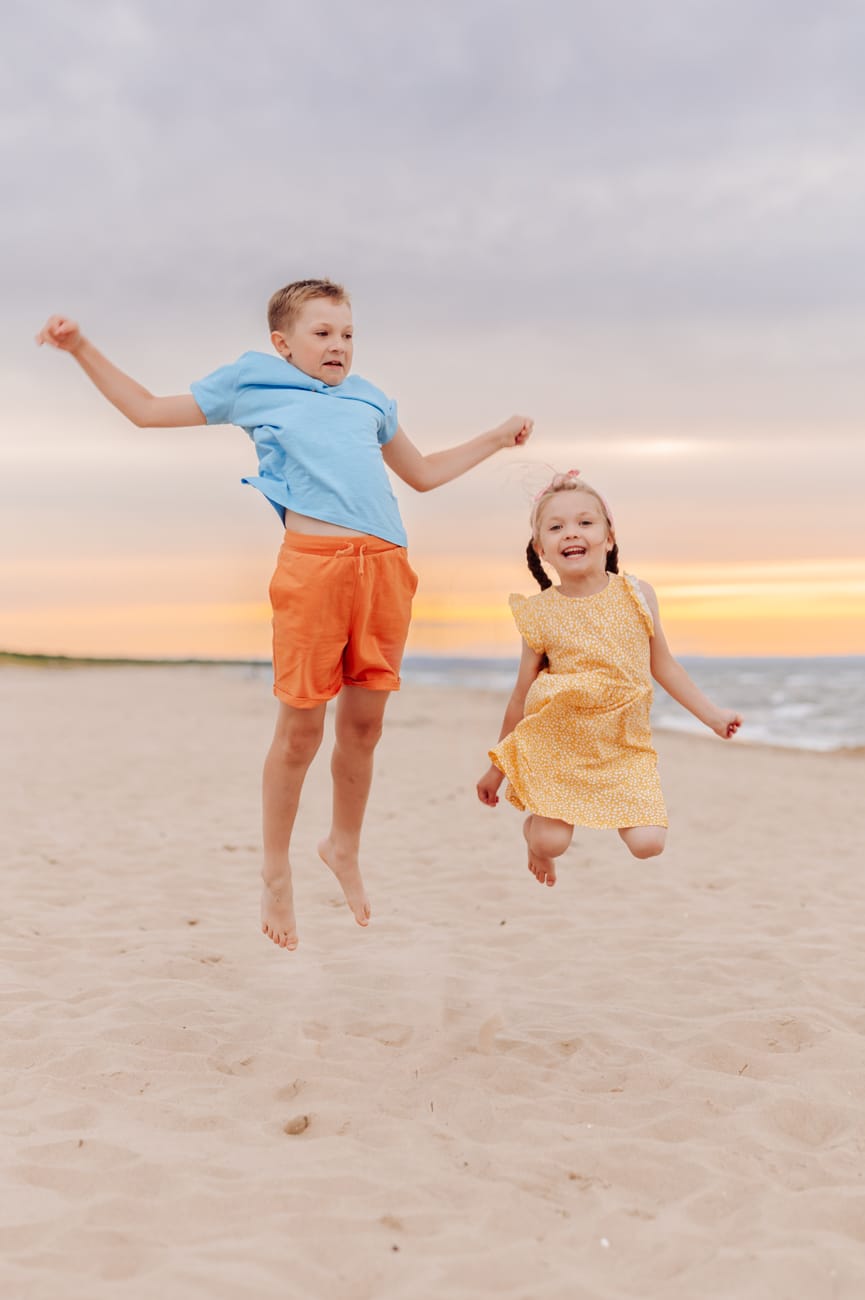 Dzieci skaczą po piasku sesja rodzinna w wakacje