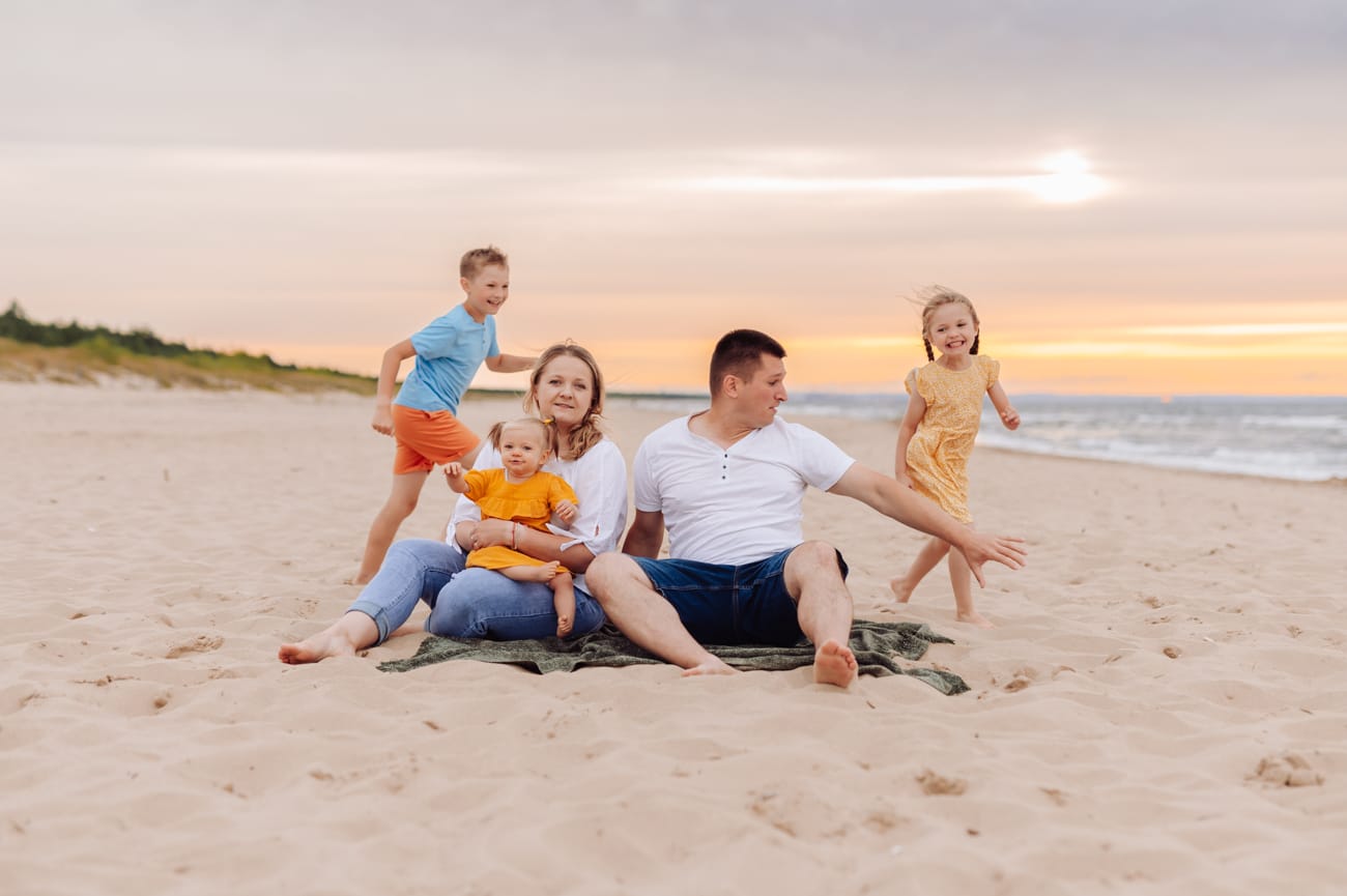 Rodzice z dzieckiem na kocu starsze dzieci biegają plaża