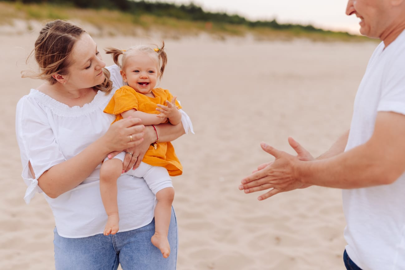 Dziewczynka śmieje się w ramionach mamy sesja nad morzem