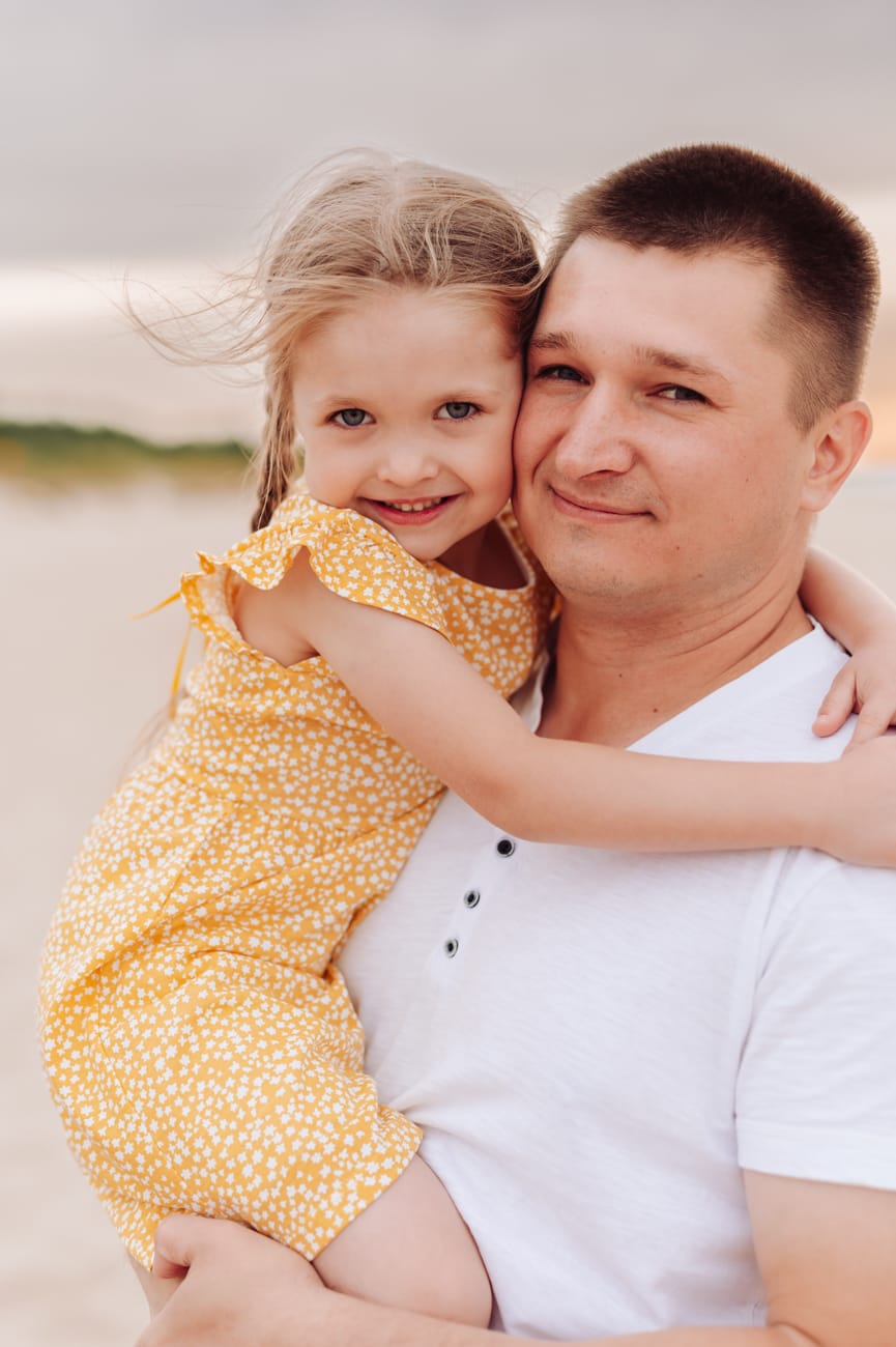 Tata przytula córkę na plaży sesja rodzinna w wakacje