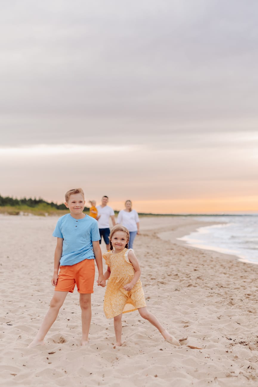 Dzieci trzymają się za ręce rodzice w tle plaża