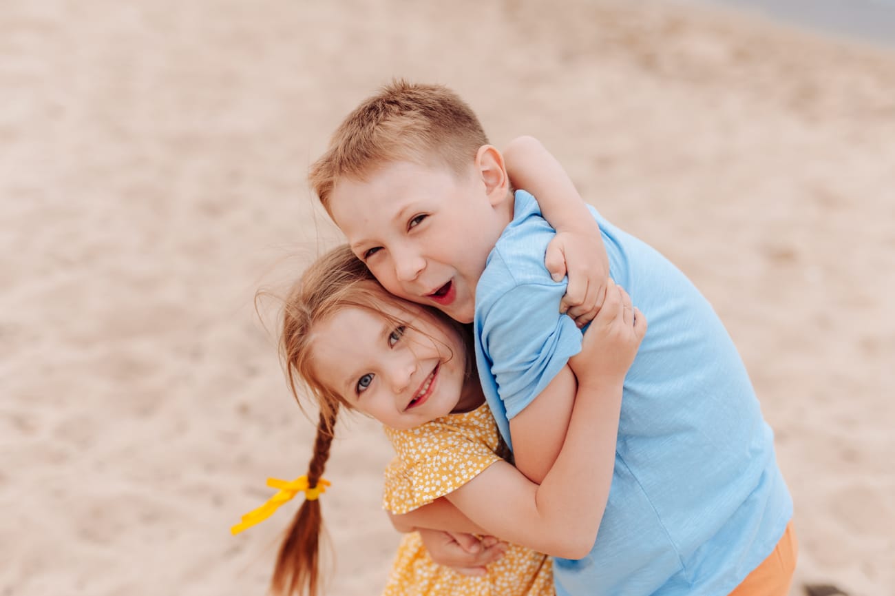 Rodzeństwo przytula się na plaży sesja rodzinna