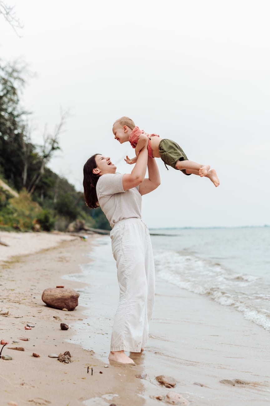 Mama podnosi dwulatka nad morzem sesja rodzinna