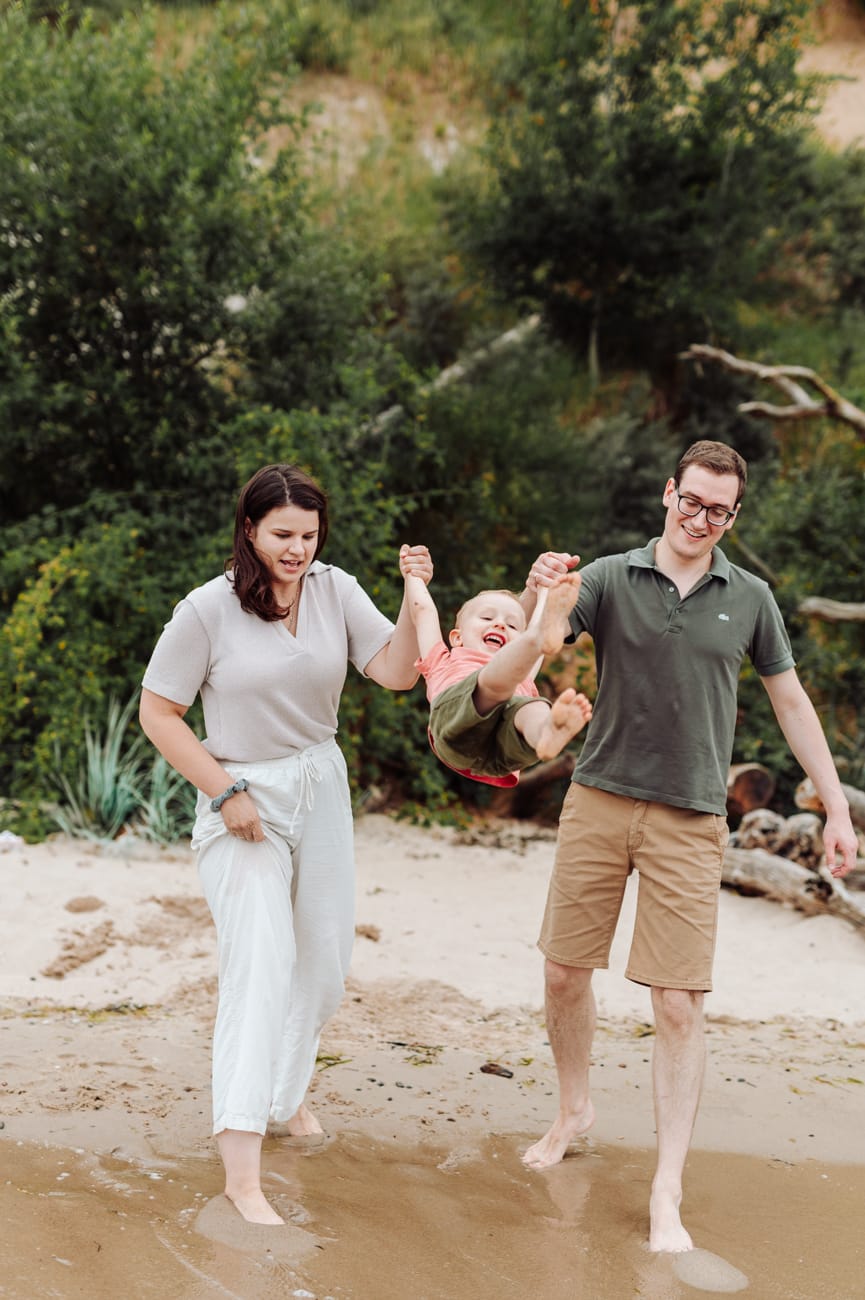 Rodzice huśtają dwulatka na brzegu morza Gdynia