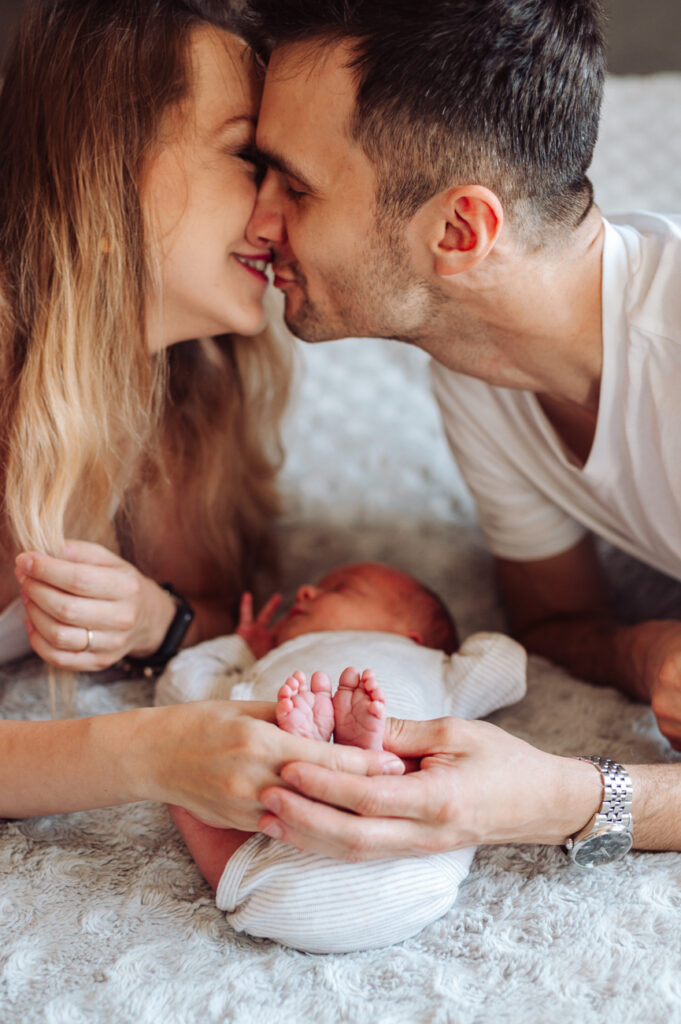 Mama całuje główkę noworodka sesja noworodkowa w domu