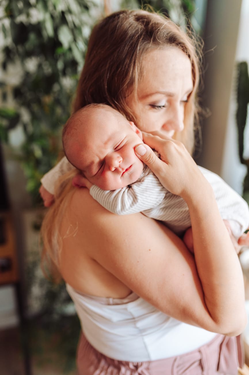Mama z noworodkiem na tle roślin sesja w domu Gdańsk
