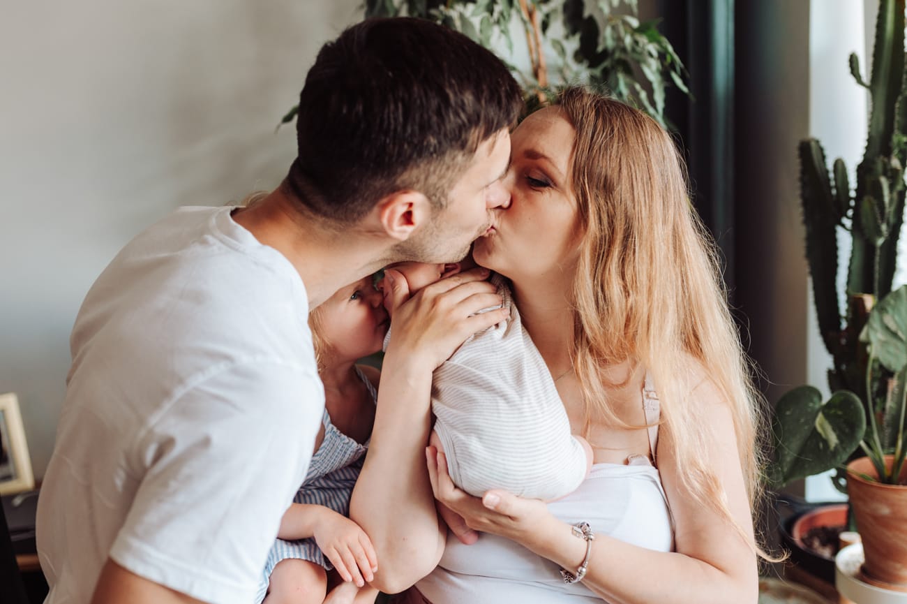 Rodzice całują się sesja noworodkowa z rodzeństwem Gdańsk
