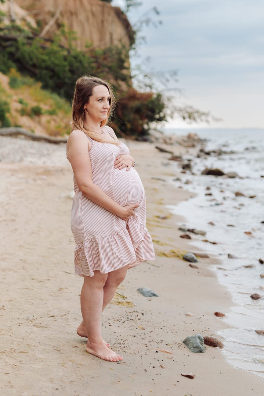 Mama w ciąży patrzy na morze sesja ciążowa Gdynia