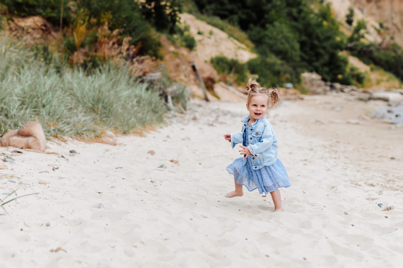 Dwulatka biegnie po plaży sesja ciążowa ze starszym dzieckiem