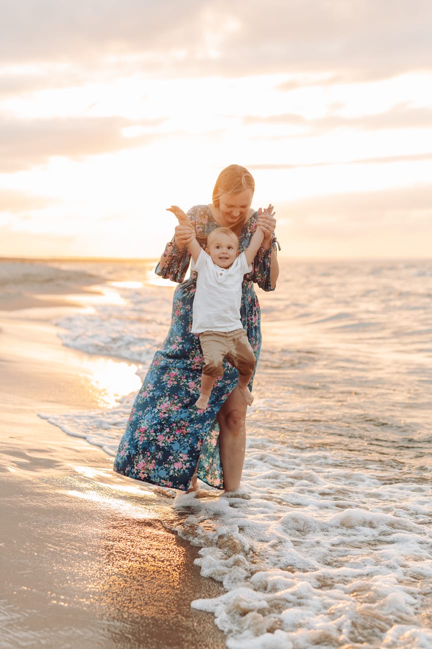 Mama podnosząca synka o zachodzie słońca.