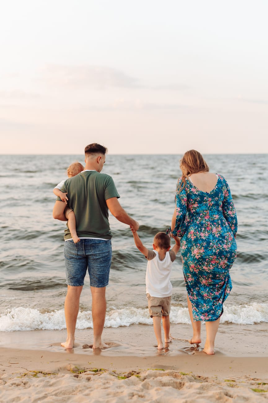 Rodzina idąca w stronę morza o zachodzie słońca.