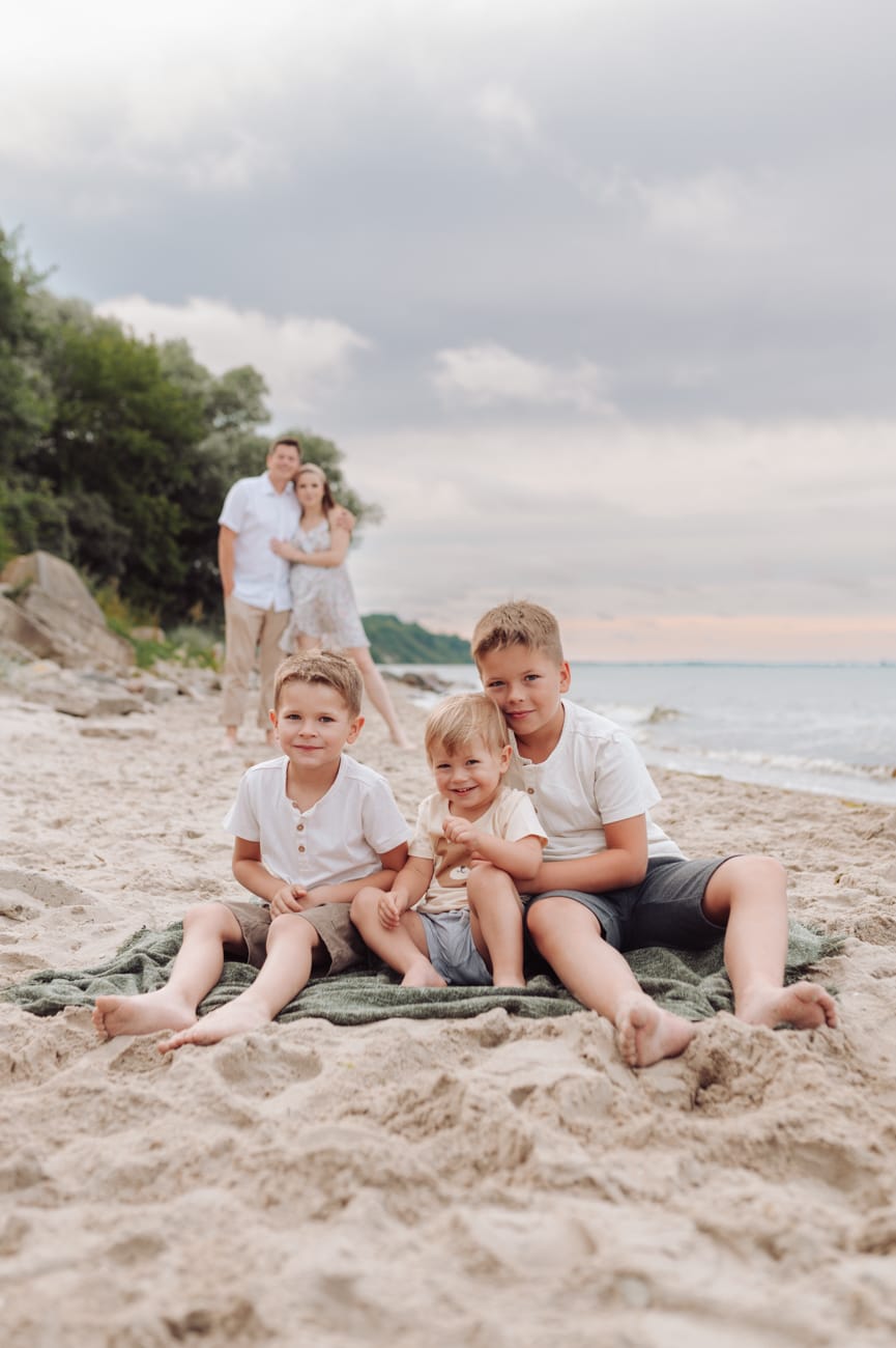 Trzej bracia na kocu na plaży rodzice w tle Gdynia