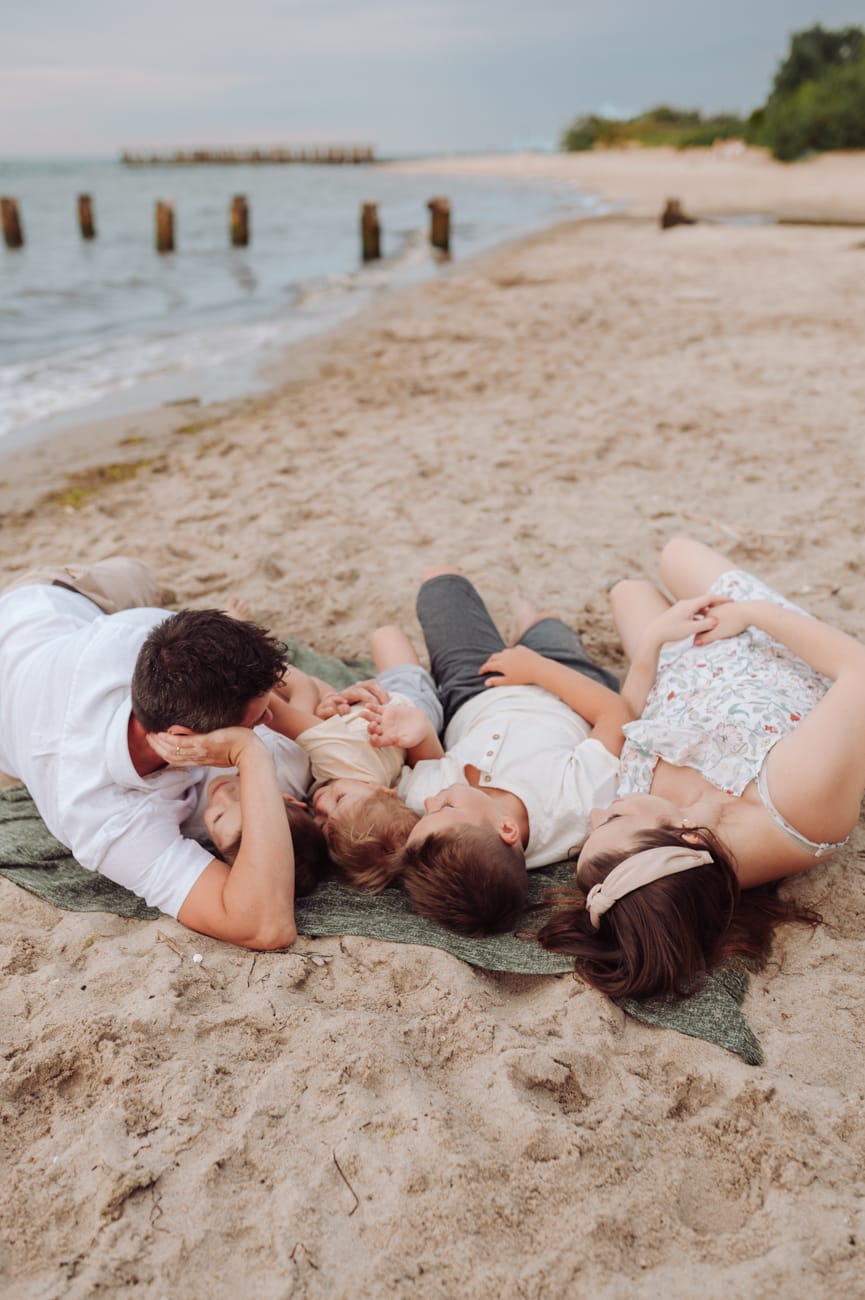 Rodzina leży na plaży zachód słońca sesja ciążowa Gdynia