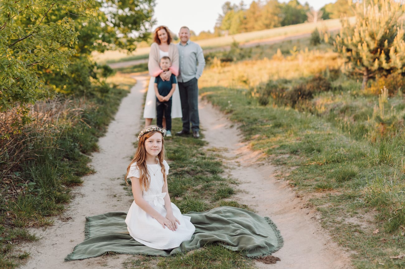 Dziewczynka na kocu rodzina w tle plener komunijny