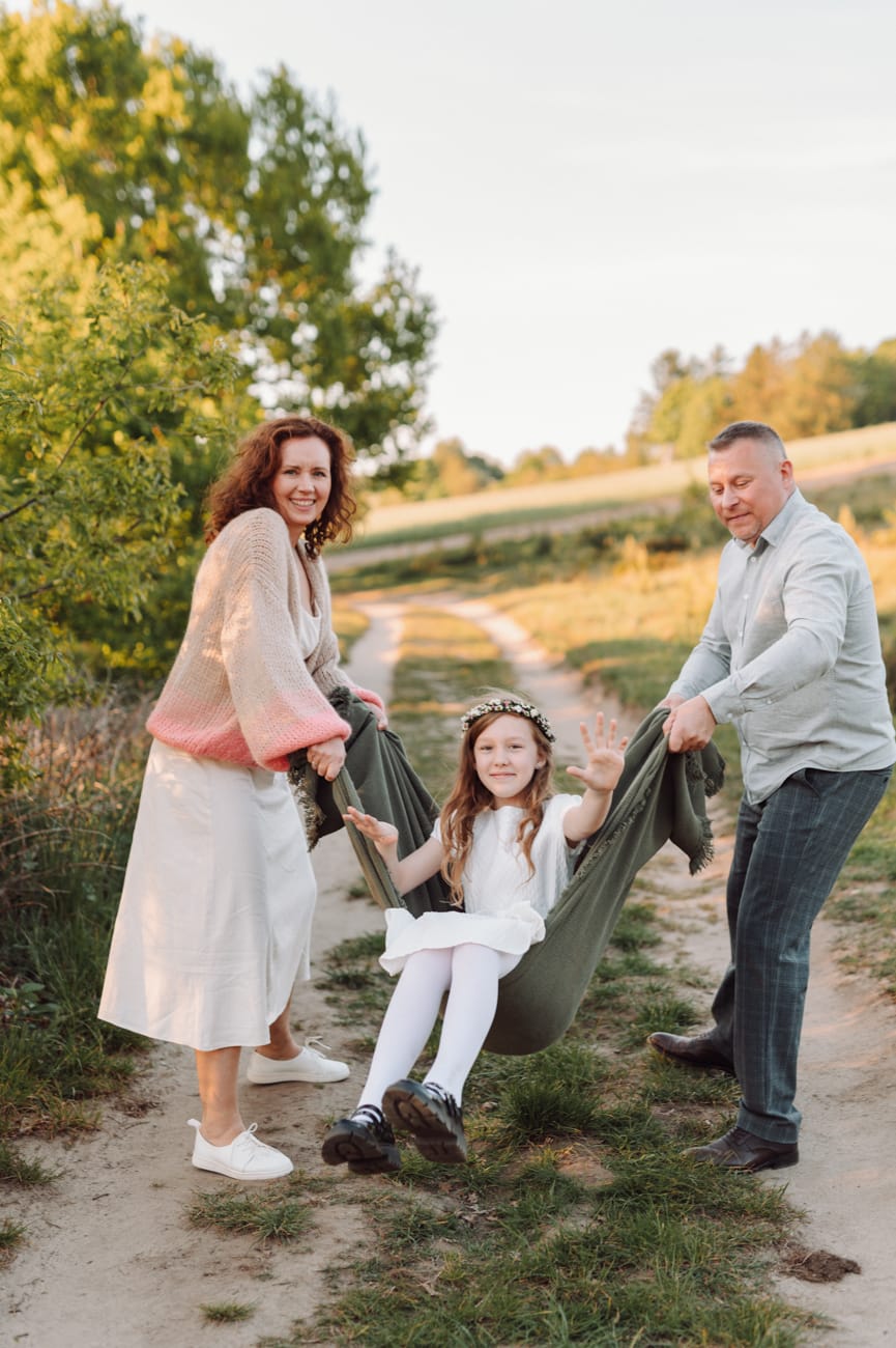 Rodzice huśtają córkę w kocu plener komunijny