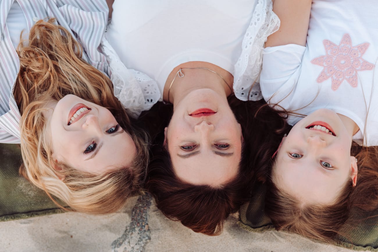 Portret mamy z nastoletnimi córkami, które leżą na plaży - sesja z nastolatkami. 