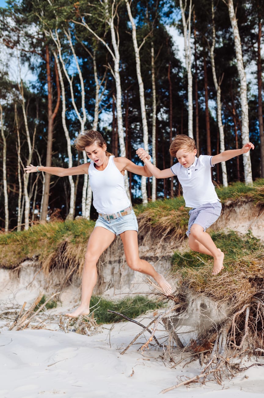 Mama z synem skaczą z konarów drzew sesja nad morzem