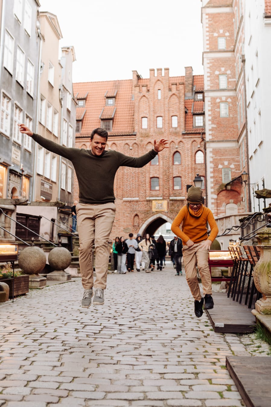 Tata z synem skaczą przy kamienicy podczas spontanicznej miejskiej sesji z dziećmi w Gdańsku.
