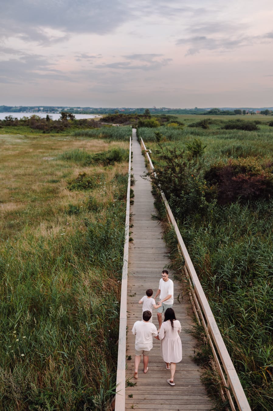 Rodzina widziana z góry podczas spaceru kładką nad łąkami w Rewie. 
