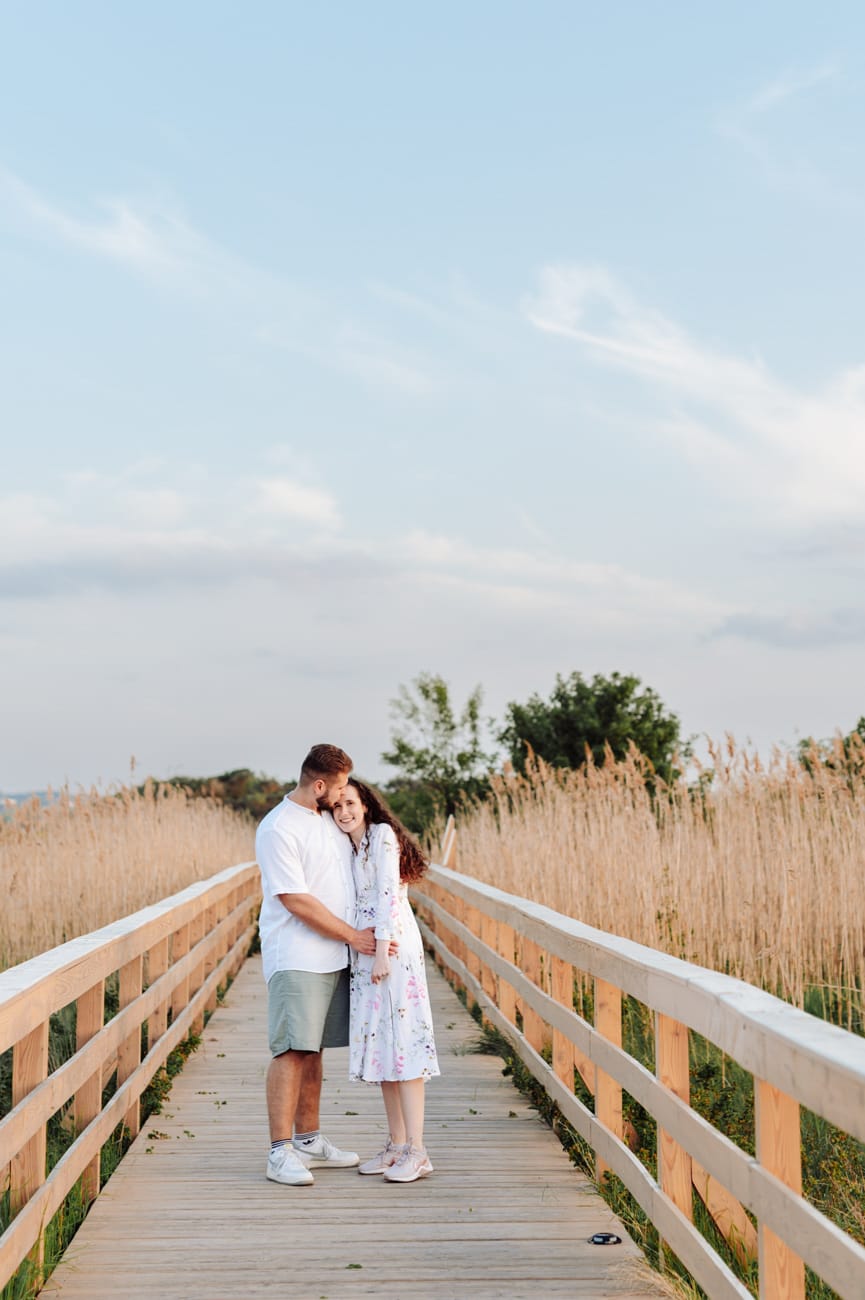 Para przytula się na drewnianej kładce nad łąkami sesja narzeczeńska
