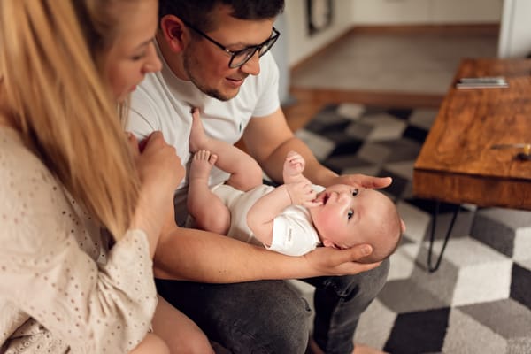 Naturalna sesja niemowlęca w domu rodzice tulą niemowlę
