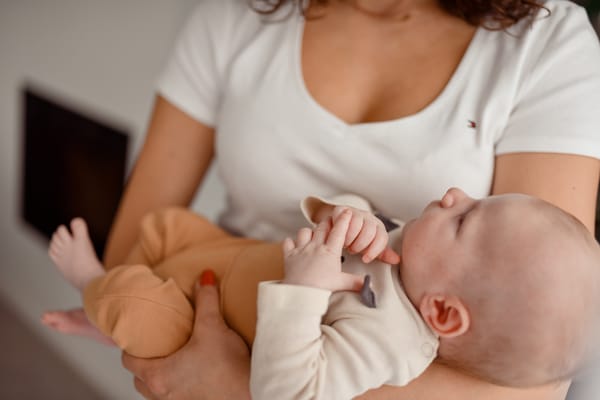Sesja niemowlęca w domu Gdynia niemowlę śpi na rękach rodziców