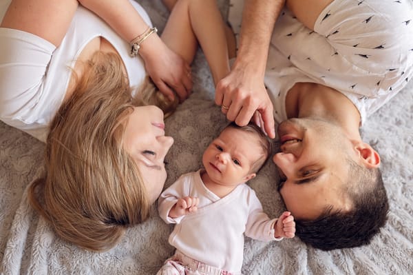 Sesja noworodkowa w domu Gdańsk rodzina z noworodkiem na łóżku