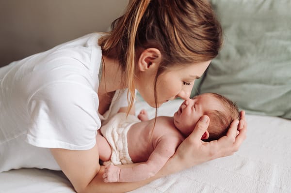 Mama całuje główkę noworodka sesja noworodkowa w domu